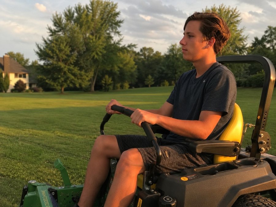 John Dever mowing a Northwoods lawn at golden hour